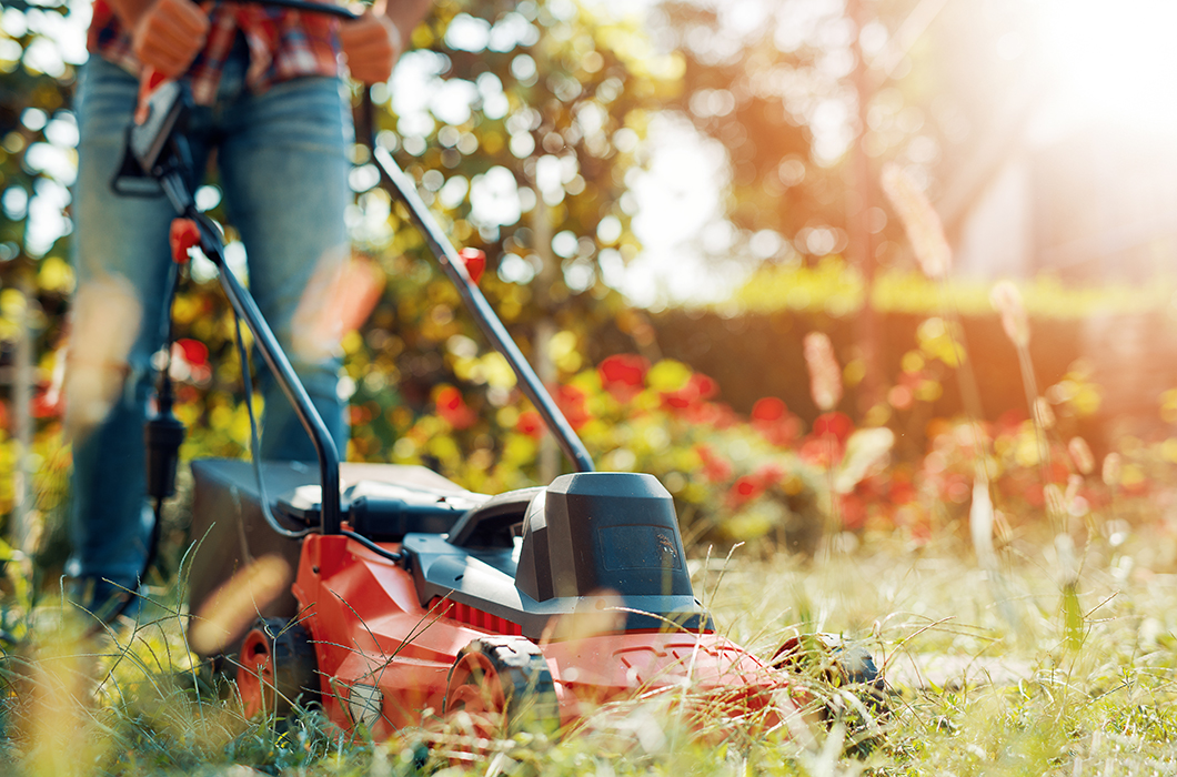 Close up of man cutting the lawn with electric mower.