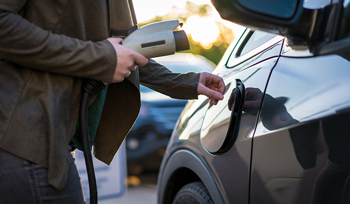 Young woman charging electric vehicle