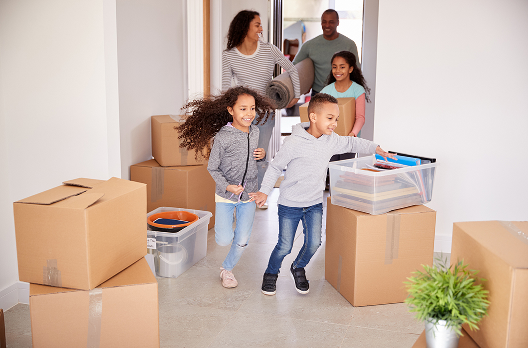 Smiling family carrying boxes Into new home on moving day.