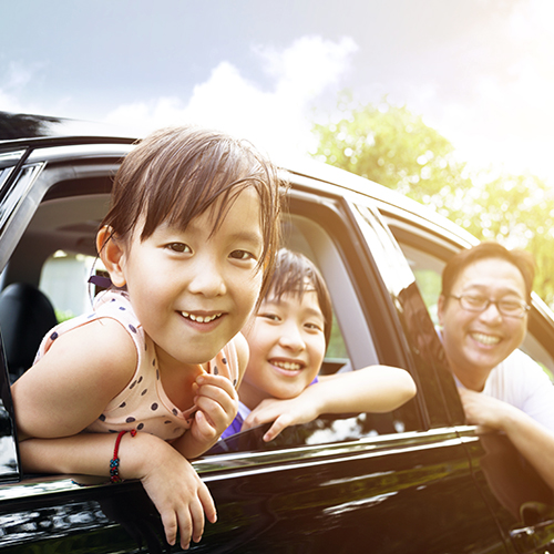 Happy little girl with family sitting in the car