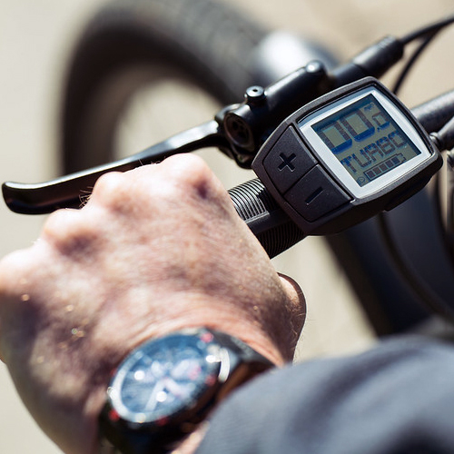 Close up of man's hand on ebike handlebars.