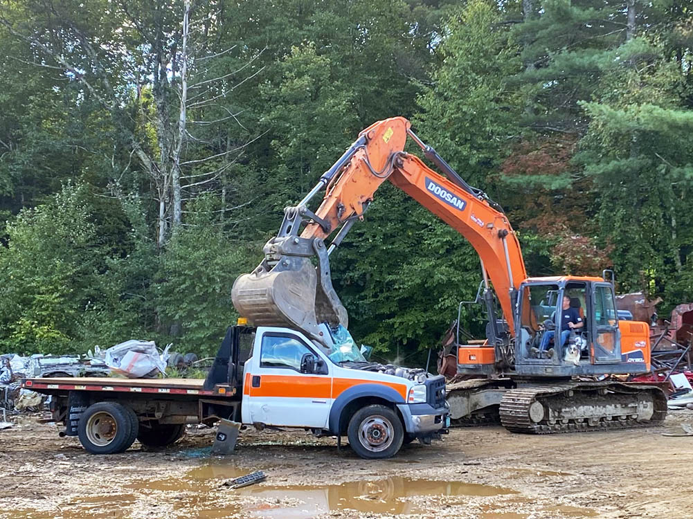 Truck being crushed by excavator.