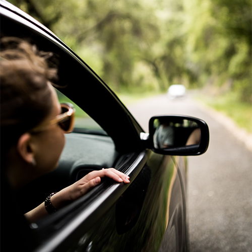 Person looking outside the window in the passenger seat while car is moving