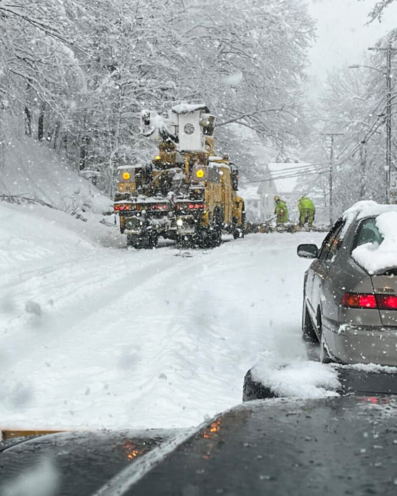 Snowy scene with a truck and linemen fixing a down power line in the road